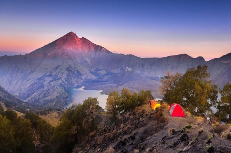 Rinjani crater rim sunrise view with camping tents overlooking Segara Anak Lake Lombok